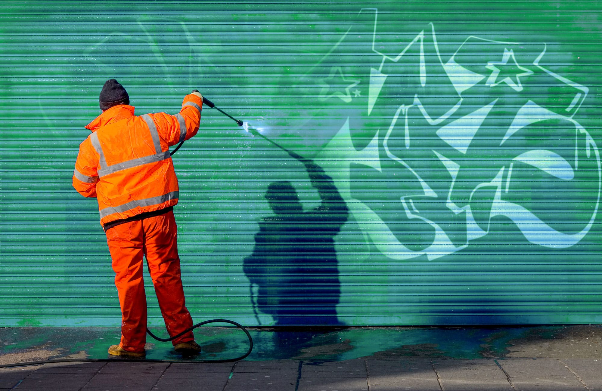 Graffiti Removal during processus. Guy on the left with gun removing graffiti quebec